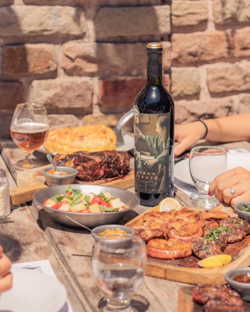 Mesa servida con malbec, pan y varios platos